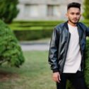 Stylish indian beard man at black leather jacket. India model po Stylish indian beard man at black leather jacket. India model posed at green garden of city.